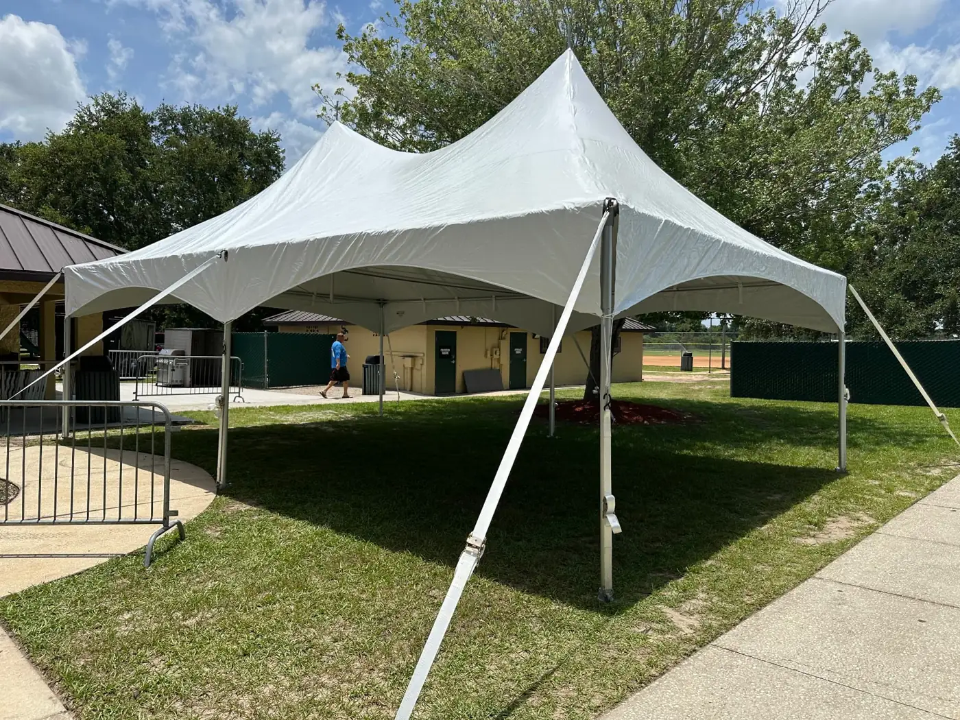 White double-peak tent with open sides and support poles on grass